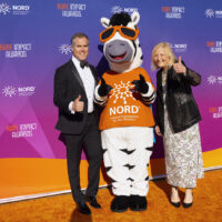 Host Peter Alexander of NBC News and NORD CEO Pamela Gavin with NORD mascot NORDY the zebra on the orange carpet