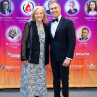 NORD CEO Pamela Gavin and host Peter Alexander in front of the wall of 2024 Rare Impact Award winners